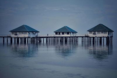 Stilt houses in sea against sky