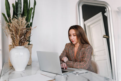 A business woman works online using a laptop phone and technology while sitting in the office