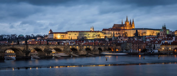 Arch bridge over river against buildings in city