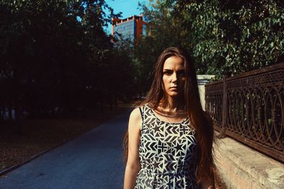 Portrait of young woman standing against trees
