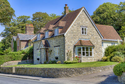 Road by house and buildings against sky