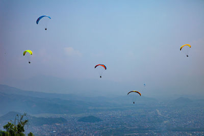 People paragliding against clear blue sky