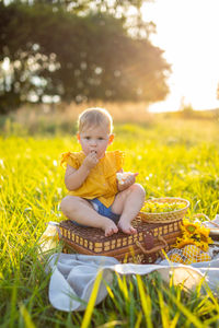 Full length of cute girl sitting on grass in field