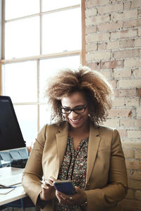 Happy businesswoman using smart phone in office