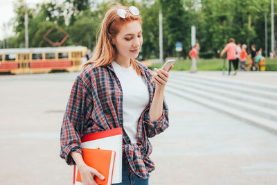 Young woman with arms raised standing in city