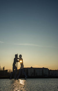 Reflection of people in water at sunset