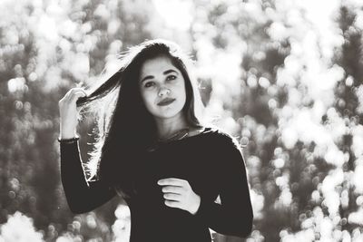 Portrait of young woman standing against tree