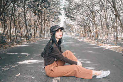 Young woman sitting on road in forest