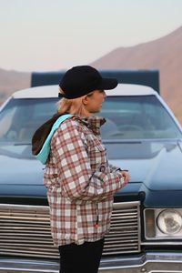 Rear view of a girl standing against car