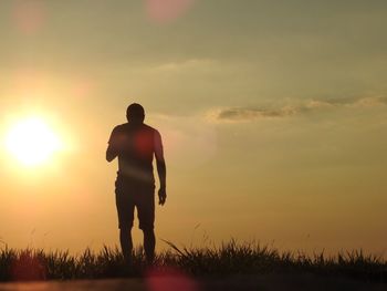 Silhouette man walking on landscape at sunset