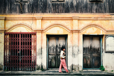 Side view of woman walking on footpath by building