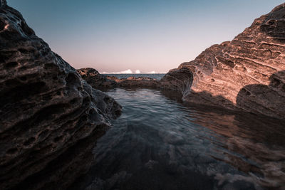 Rock formations in sea against clear sky