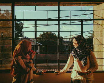 Smiling friends standing at window