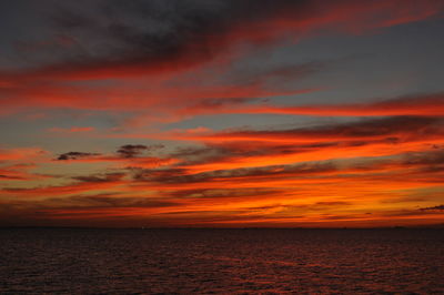 Scenic view of sea against dramatic sky during sunset