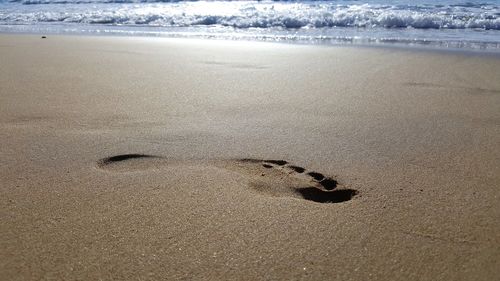 Close-up of footprints on sand at beach