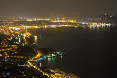 High angle view of illuminated buildings by river at night