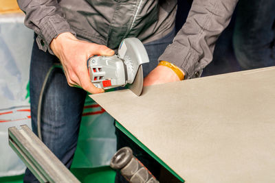 In the male hands of a master, a grinder with a diamond cutting wheel cuts ceramic tiles. copy space