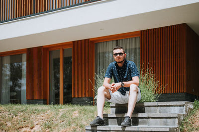 Full length of man sitting on staircase against building