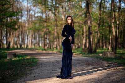 Full length portrait of woman standing in forest