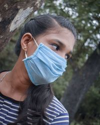 Close-up of young woman wearing mask looking away outdoors