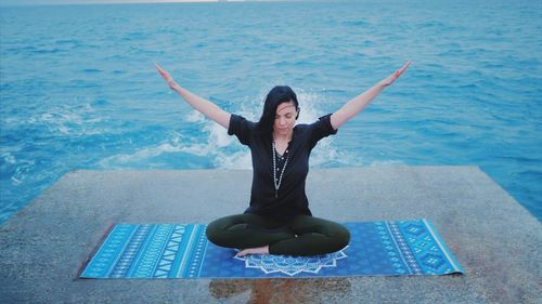 Full length of woman performing yoga against sea