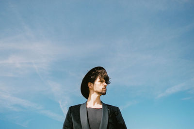 Low angle view of young man standing against sky