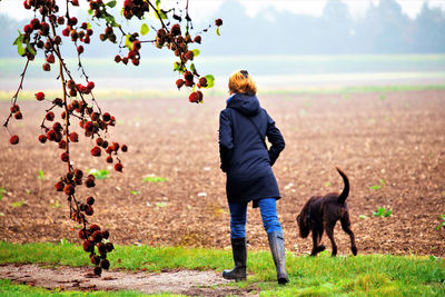 Rear view of woman with dog walking on field