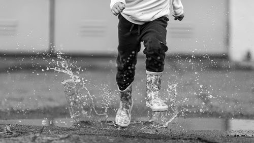 Low section of man running on puddle