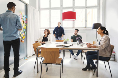 Mid adult businessman giving presentation to colleagues in conference room