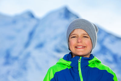 Portrait of young woman standing against snowcapped mountain