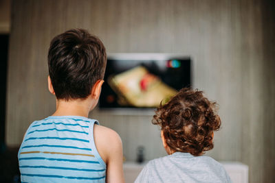 Two boys are watching an interesting tv show on tv. children's home rest. home activity. 
