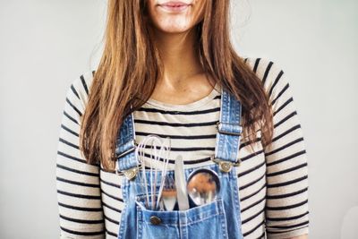 Young woman standing against white wall