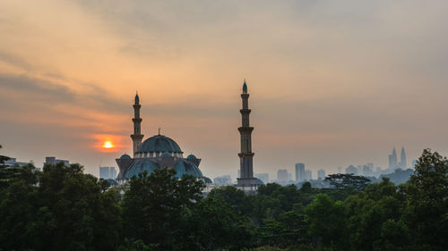 Trees and buildings against sky during sunset