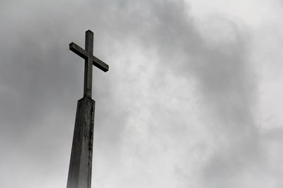 Low angle view of cross on wooden post against sky