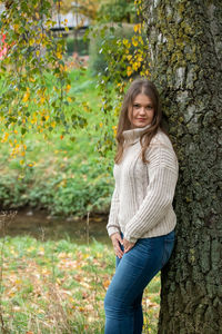 Portrait of teenage girl standing against tree trunk
