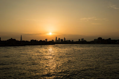 Scenic view of river in city at sunset