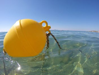 Close-up of yellow umbrella on beach against clear blue sky