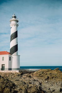 Lighthouse on beach against sky