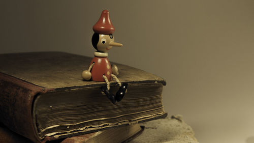 Close-up of toy on old books at table against wall