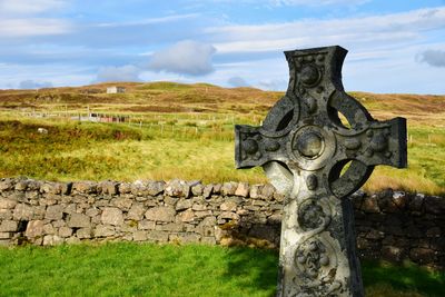 Cross on graveyard against sky