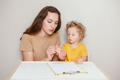 Mom drawing on paper together with baby. mother teaching kid to hold marker pencil correctly