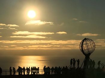 Silhouette people on beach against sky during sunset