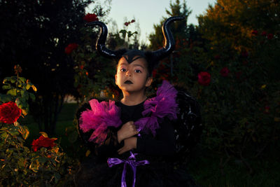 Portrait of young woman with maleficient costume standing against plants