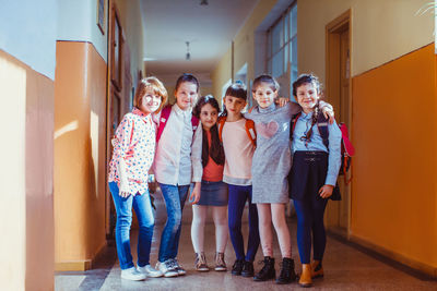 Portrait of a smiling girl standing against the wall