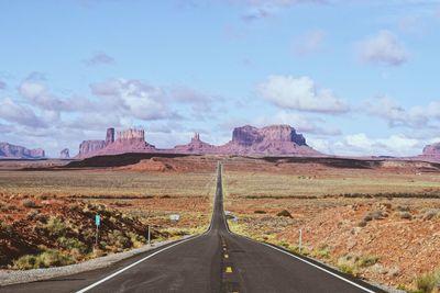 Empty road along landscape against sky