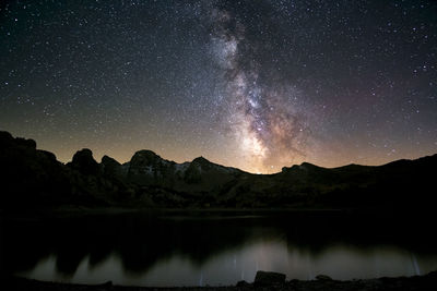 Scenic view of lake and mountains against sky at night