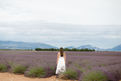 Rear view of woman standing on field against sky