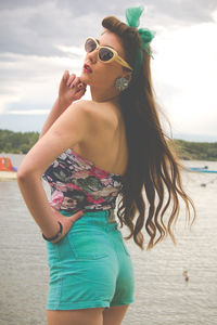 Young woman wearing sunglasses standing at beach