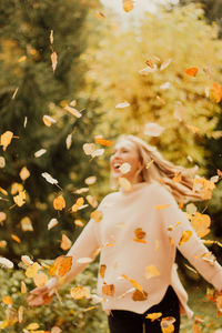 Young woman standing by tree during autumn
