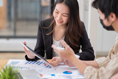 Young woman using phone while sitting on table